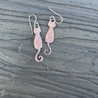 Copper cat earrings on flat surface